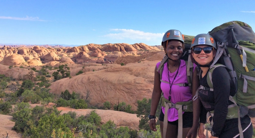 Two students smile for a photo in front of a vast desert landscape 